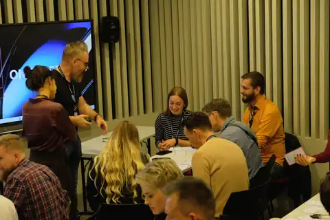 Workshop a Service Design Day 2025-ön: a résztvevők asztaloknál dolgoznak, elöl a kivetítő.