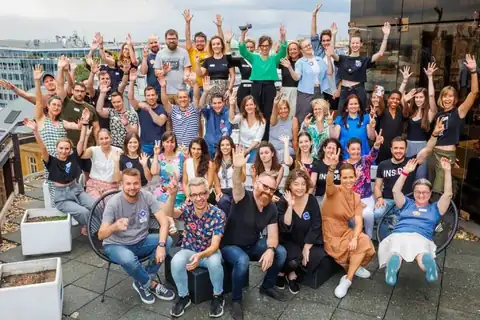 A Social Design Jam résztvevői csoportképen egy tetőteraszon, felemelt kézzel.